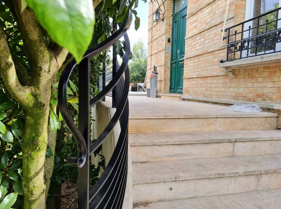 Escalier monumental en colimaçon avec rampe en fer forgé ornementée, balustres sculptés et marches en pierre naturelle