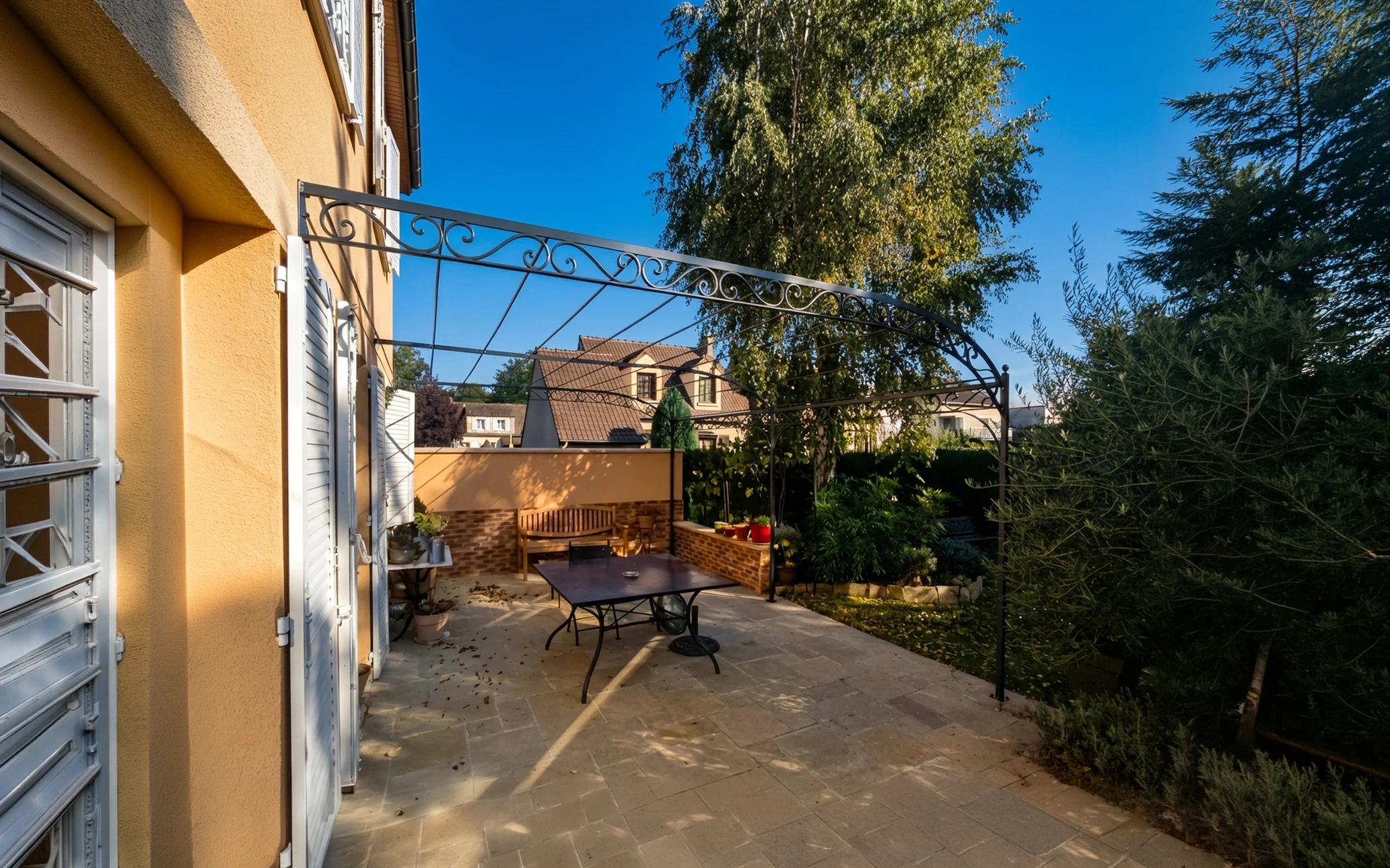 Terrasse extérieure résidentielle avec pergola métallique grise et filet de protection anti-chute
