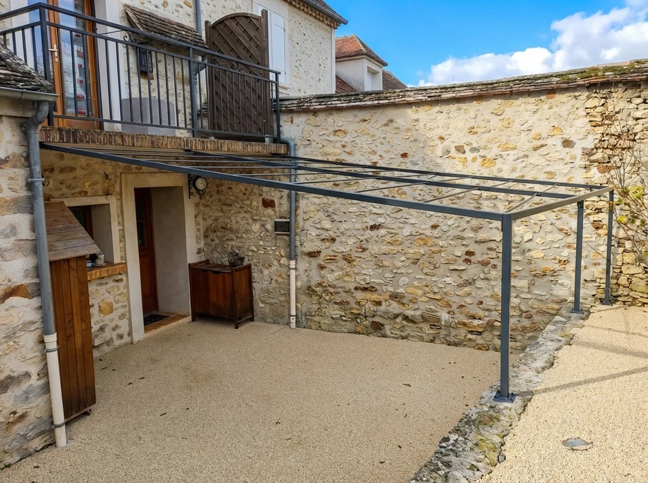 Clôture en fer forgé noir avec motifs décoratifs ondulés et volutes ornementales, installée le long d'un chemin