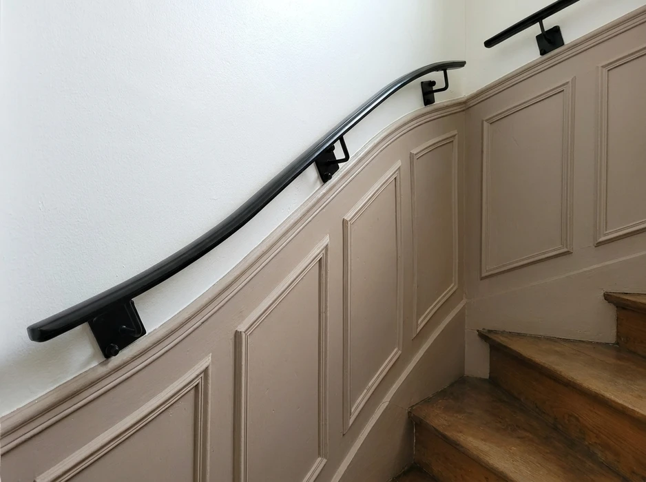 Entrée résidentielle avec portail en fer forgé décoratif à double battant, encadré par des piliers en briques rouges surmontés de lanternes